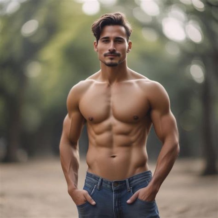 a man without a shirt is standing in the street with his shorts rolled